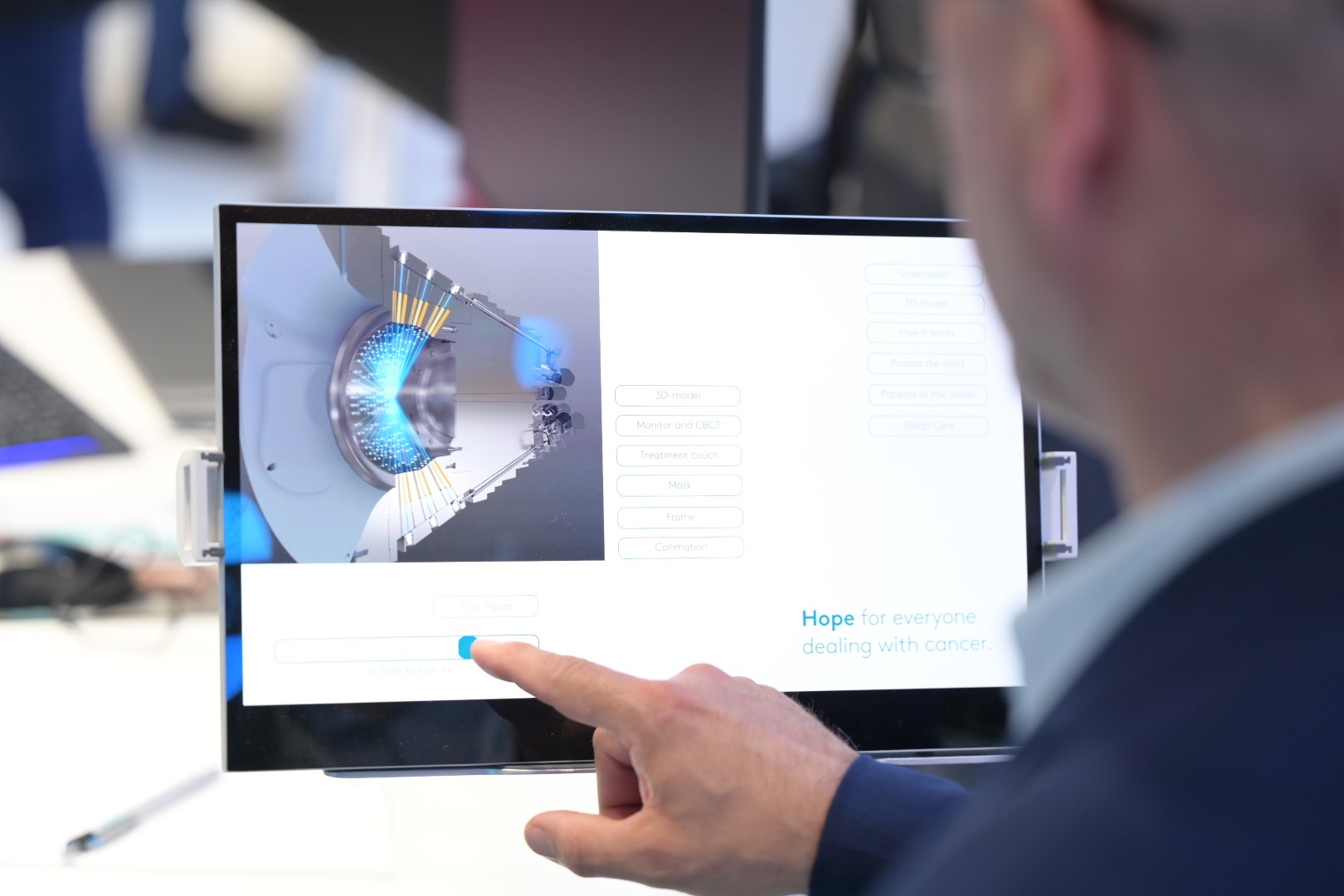 An expert demonstrating Elekta software on a touch screen