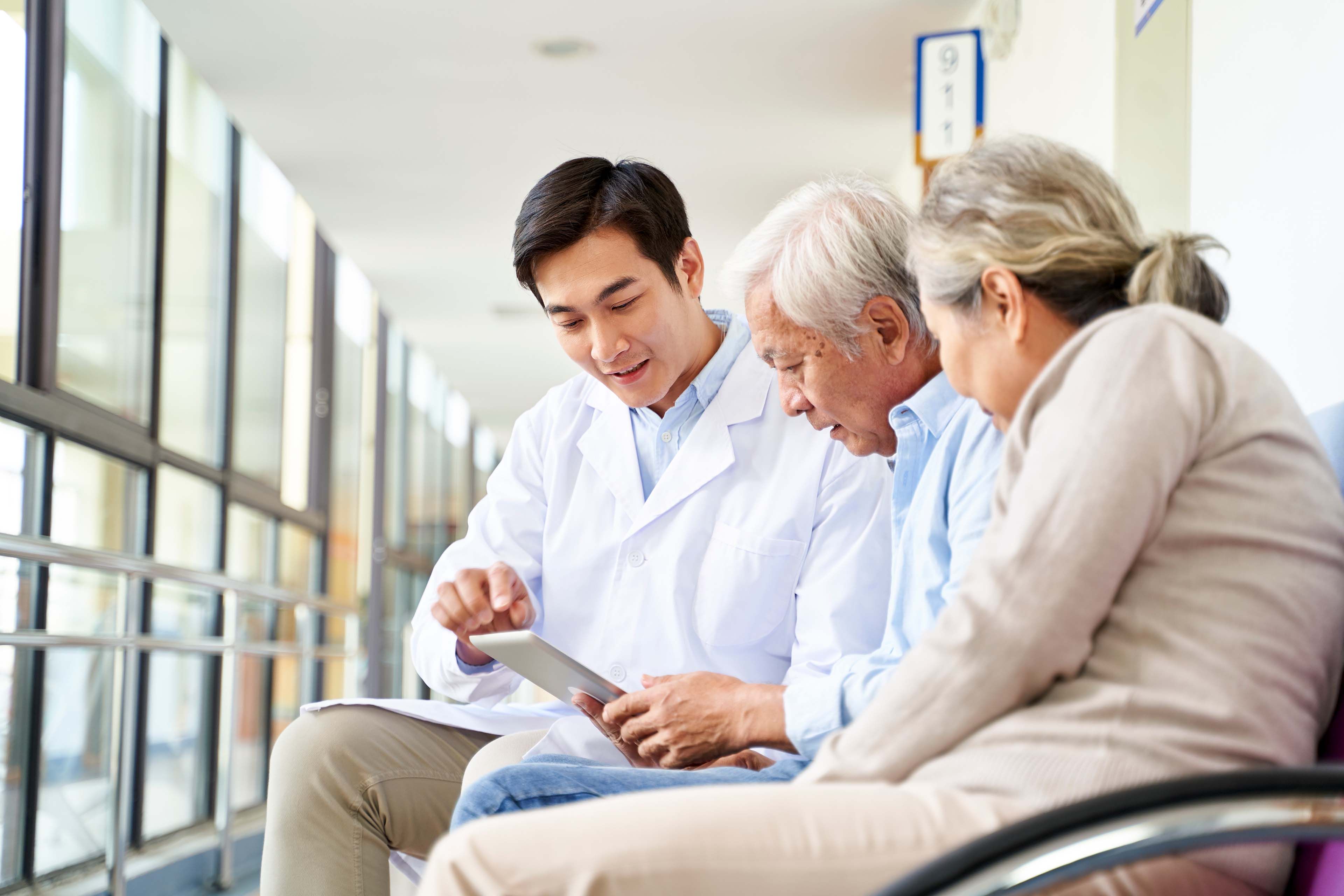 Doctor looking at a tablet with a male patient and his wife