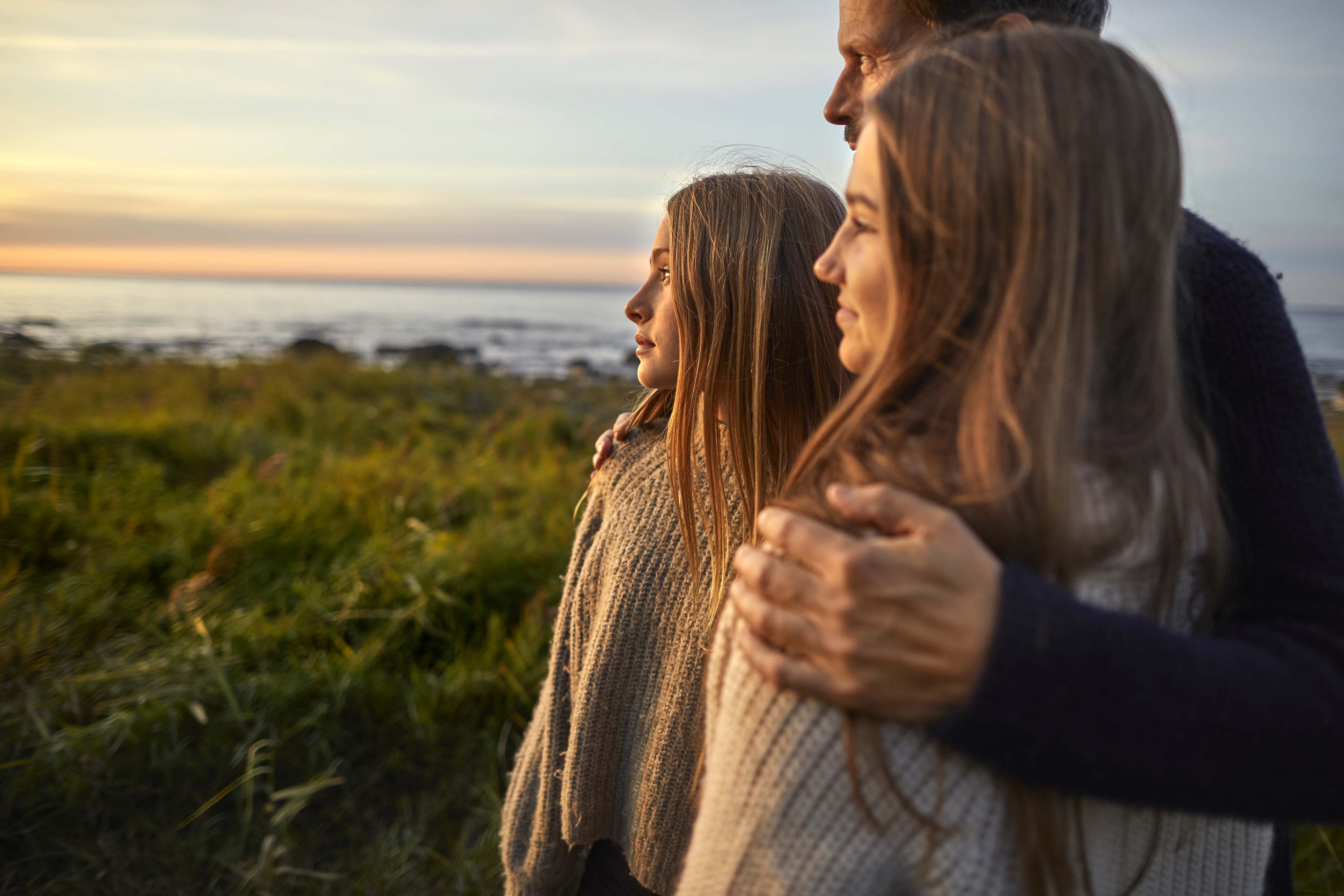 Father and daughters embracing by the seaside